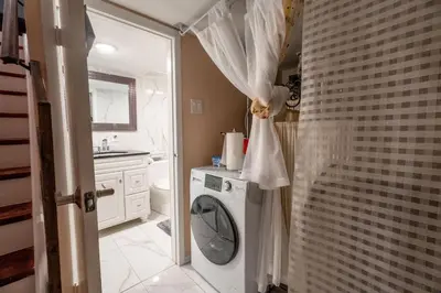 a bathroom with a washing machine and a sink at Stylish 2BR Home with Front Yard and Free Parking in Toronto
