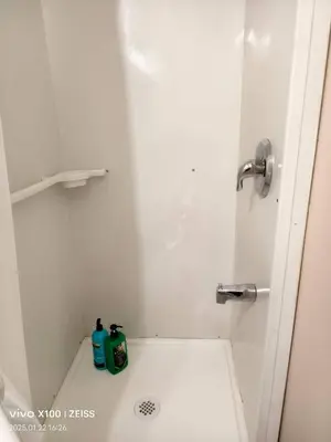 a bathroom with a shower with two bottles on the floor at Toronto Travellers Home in Toronto