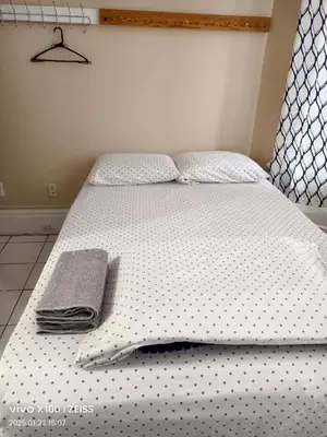 a bed with white sheets and a towel on it at Toronto Travellers Home in Toronto