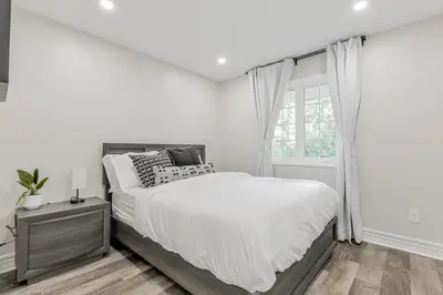 a white bedroom with a bed and a window at Innisfil retreat, hot tub, Sauna, EV plug, Generac in Innisfil