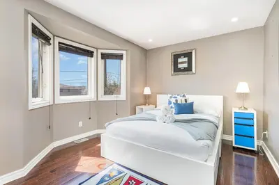 a bedroom with a white bed and two windows at Home in Richmond Hill in Richmond Hill