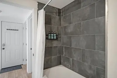 a bathroom with a gray tiled wall at The Willow Suite Near DT & Hospital in Peterborough