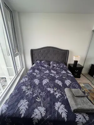 a bedroom with a bed with a blue comforter at Vaughan Cozy 1 Bedroom Condo in Vaughan