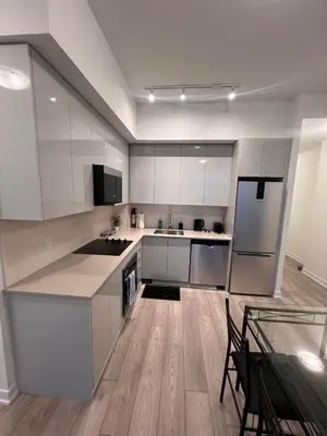 a kitchen with white cabinets and a wooden floor at Vaughan Cozy 1 Bedroom Condo in Vaughan