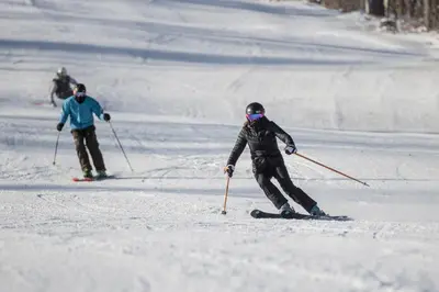 a group of people skiing down a snow covered slope at Blue Mountain Resort Village Suites in Blue Mountains