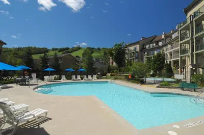 a large swimming pool with chairs and umbrellas at Blue Mountain Resort Village Suites in Blue Mountains