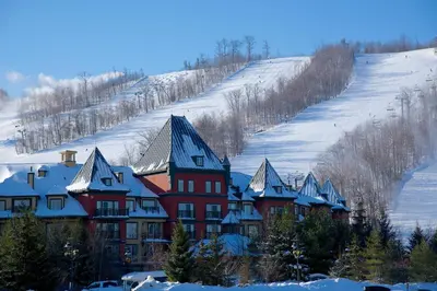 a large red building with snow covered roofs on a hill at Blue Mountain Resort Village Suites in Blue Mountains