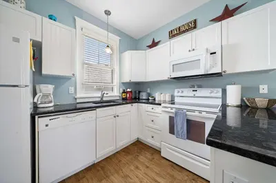 a kitchen with white cabinets and black counter tops at The Catbird - 28 Butternut in Cherry Valley