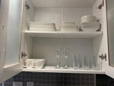 a white cabinet with plates and glasses and dishes on it at Cozy Two-Bedroom Luxury Suite near Toronto Airport in Mississauga