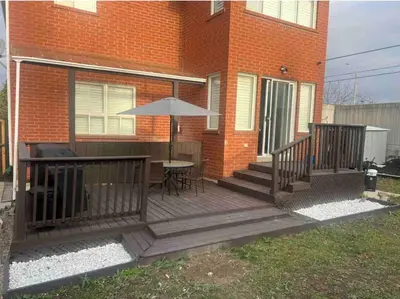 a wooden deck with a table and an umbrella at Cozy Two-Bedroom Luxury Suite near Toronto Airport in Mississauga