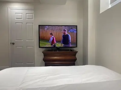 a flat screen tv sitting on a stand in a bedroom at Cozy Two-Bedroom Luxury Suite near Toronto Airport in Mississauga
