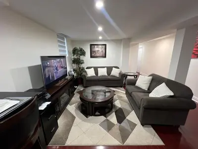 a living room with a couch and a flat screen tv at Cozy Two-Bedroom Luxury Suite near Toronto Airport in Mississauga