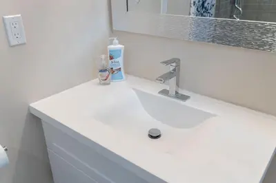 a bathroom sink with a bottle of soap and a mirror at The Bloor Spadina Getaway With 3-Bedroom and Private Patio in Toronto