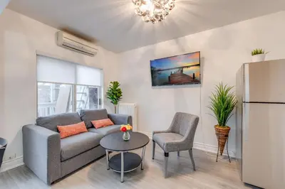 a living room with a couch and a table and a refrigerator at The Bloor Spadina Getaway With 3-Bedroom and Private Patio in Toronto