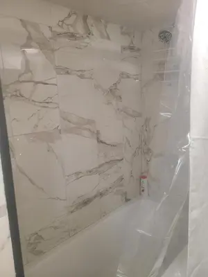 a bathroom with white marble walls and a tub at 132 Chatham ave in Toronto