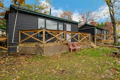 a house with two pink chairs in front of it at 2-Bedroom Cottage #10 - Pitch Pine in Gravenhurst