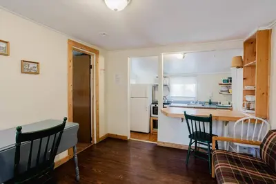 a living room with a table and chairs and a kitchen at 1-Bedroom Cottage #1 - White Pine in Gravenhurst