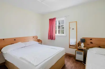 a bedroom with two beds and a mirror at 1-Bedroom Cottage #1 - White Pine in Gravenhurst