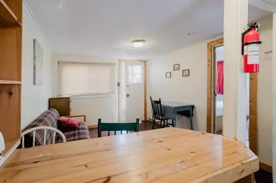 a living room with a wooden table and a dining room at 1-Bedroom Cottage #1 - White Pine in Gravenhurst