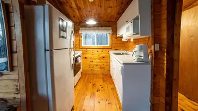 a kitchen with a white refrigerator and wooden walls at Muskoka Lakeview Cottage - Pier 100 #40 in Port Carling