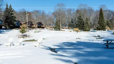 a snow covered yard with chairs and a picnic table at Lake Muskoka Deluxe 2-bdrm Cottage - Pier 100 #60 in Port Carling