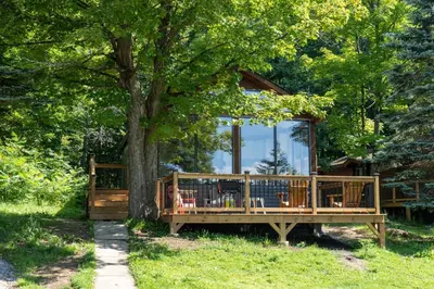 a wooden house with a tree in front of it at Lake Muskoka Deluxe 2-bdrm Cottage - Pier 100 #60 in Port Carling