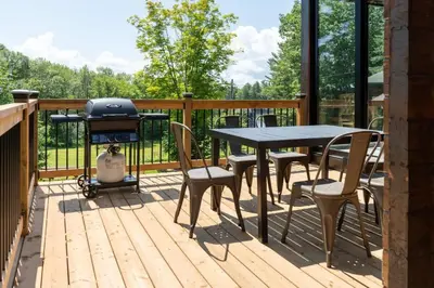 a deck with a grill and a table and chairs at Lake Muskoka 3-bedroom Cottage - Pier 100 #30 in Port Carling