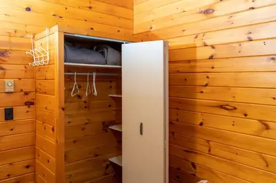 a bedroom with wooden walls and a white refrigerator at Lake Muskoka Deluxe 3-bdrm Cottage - Pier 100 #80 in Port Carling