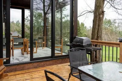 a screened in porch with a grill on the deck at Lake Muskoka Deluxe 3-bdrm Cottage - Pier 100 #80 in Port Carling