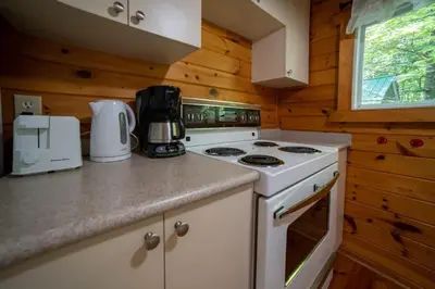 a kitchen with a white stove top oven in a cabin at Lake Muskoka 3-bedroom Cottage - Pier 100 #20 in Port Carling