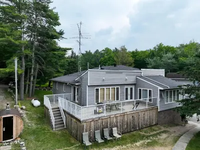 a home with a large deck and a house at Muskoka Lakefront 4-bdrm Guest House in Port Carling
