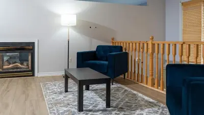 a living room with a blue chair and a table at Muskoka Lakefront 4-bdrm Guest House in Port Carling
