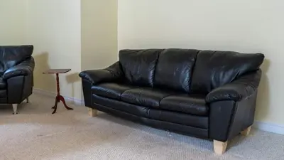 a black leather couch in a living room with a table at Muskoka Lakefront 4-bdrm Guest House in Port Carling
