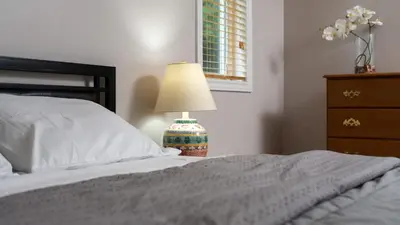 a bedroom with a bed with a lamp and a dresser at Muskoka Lakefront 4-bdrm Guest House in Port Carling