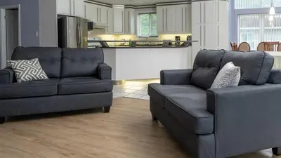 a living room with two couches and a kitchen at Muskoka Lakefront 4-bdrm Guest House in Port Carling