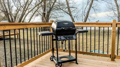 a grill on a deck next to a fence at 2-bedroom Lake Front Cottage in Harwood ON #6 in Harwood