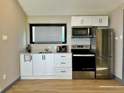 a kitchen with white cabinets and a stainless steel refrigerator at 2-bedroom Lake Front Cottage in Harwood ON #6 in Harwood
