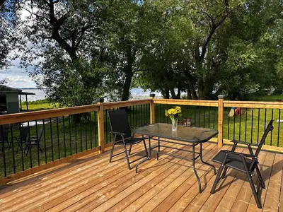 a patio with a table and chairs on a deck at 2-bedroom Lake Front Cottage in Harwood ON #6 in Harwood