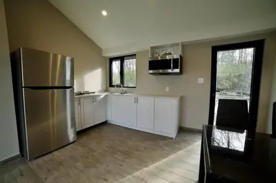 a kitchen with a stainless steel refrigerator and white cabinets at 1-bedroom Townhouse in Harwood #3 in Harwood