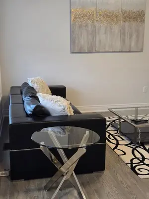 a living room with a black couch and a glass table at Modern 4 Bedroom Home -Oakville in Oakville