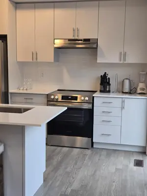 a kitchen with stainless steel appliances and white cabinets at Modern 4 Bedroom Home -Oakville in Oakville