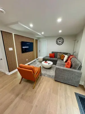 a living room with a gray couch and a clock at 2 BR Private Basement Suite | Minutes from YYZ in Brampton