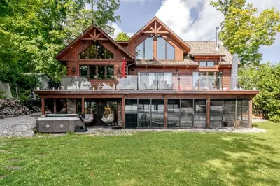 an exterior view of a log home with glass windows at Lakefront cottage with golf area BBQ pool table in Bobcaygeon