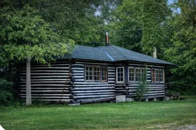 a log cabin sitting in the middle of a yard at 2-Bedroom - Balsam Lake Cottages Resort #12 in Kawartha Lakes