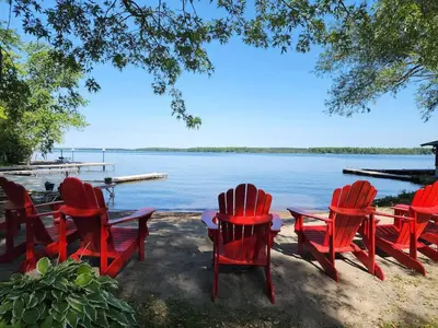 a group of red chairs and tables by the water at 2-Bedroom - Balsam Lake Cottages Resort #12 in Kawartha Lakes