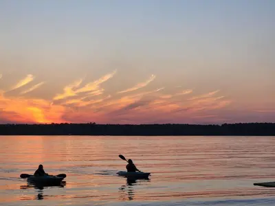 two people in canoes on a lake at sunset at 2-Bedroom - Balsam Lake Cottages Resort #12 in Kawartha Lakes