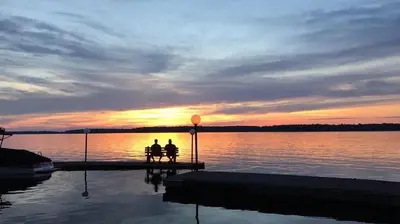 two people sitting on a bench watching the sunset at 2-Bedroom - Balsam Lake Cottages Resort #12 in Kawartha Lakes