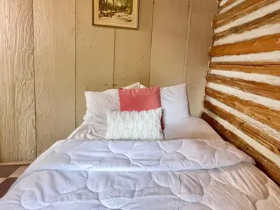 a bed with a red and white pillow on it at 1-Bedroom Balsam Lake Cottage #9 in Kawartha Lakes