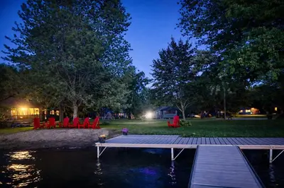 a dock with red chairs and a pond at night at Balsam Lake - 2-Bedroom Cottage #6 in Kawartha Lakes