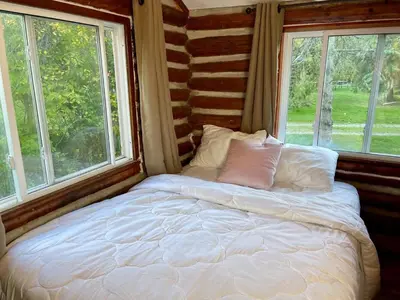 a bed sitting in a room with two windows at Balsam Lake - 2-Bedroom Cottage #6 in Kawartha Lakes